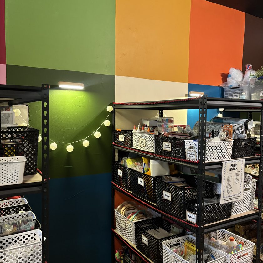 Labelled supply bins on black shelving against the colour-block wall at 414 Art Revival