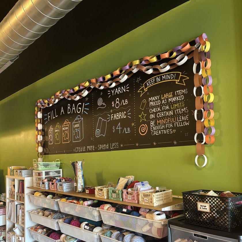 The yarn wall inside 414 Art Revival, with Fill A Bag prices chalked on the board above the bins